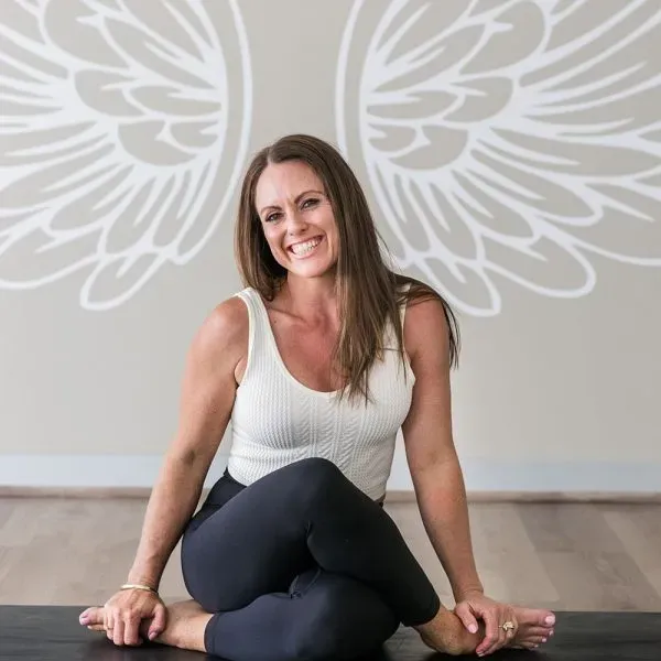 Lisa Everding, founder of Earthy Angels, seated beneath the studio wing mural