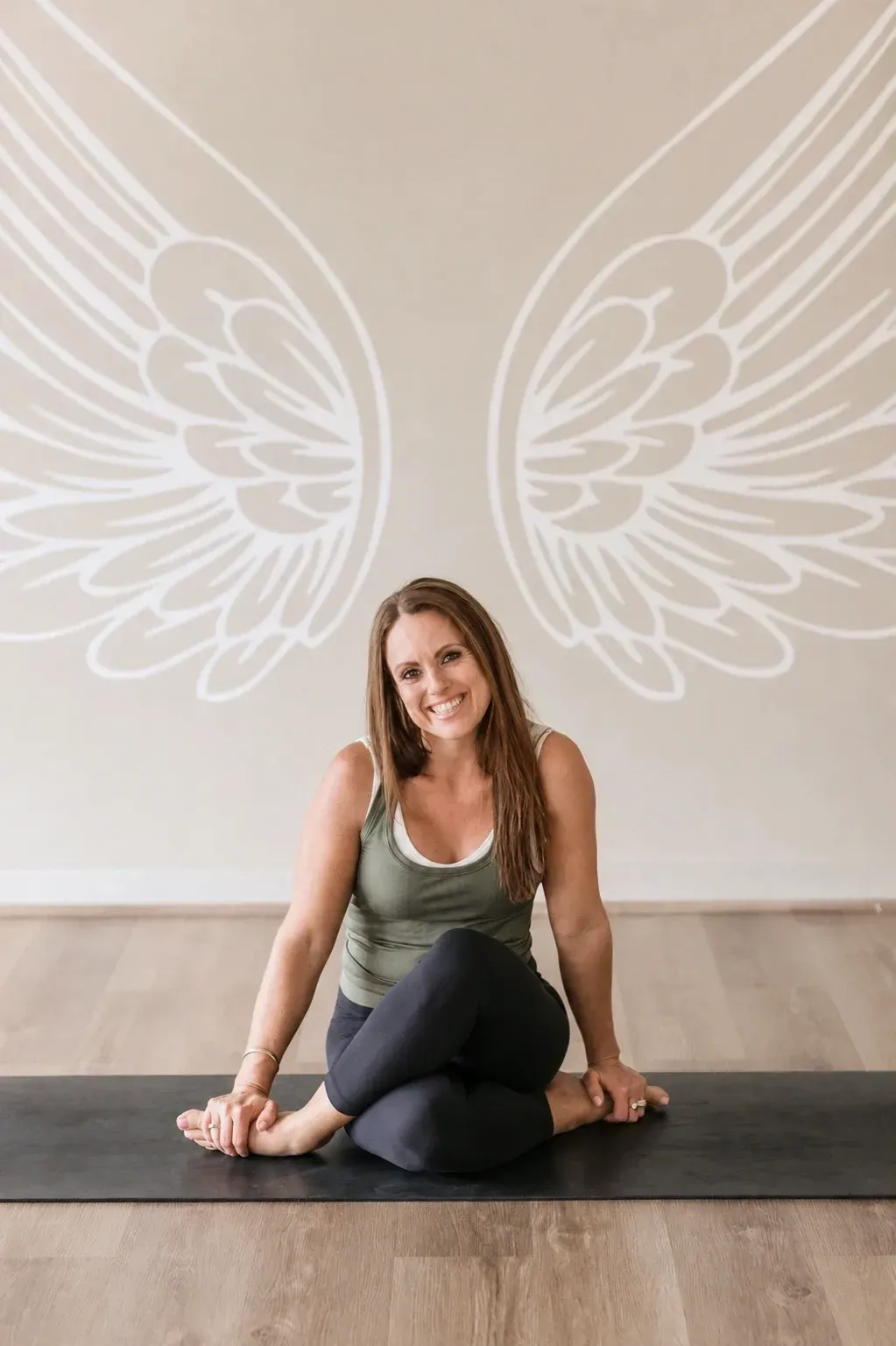 Lisa Everding, founder of Earthy Angels, seated beneath the painted wings in the Ormeau studio